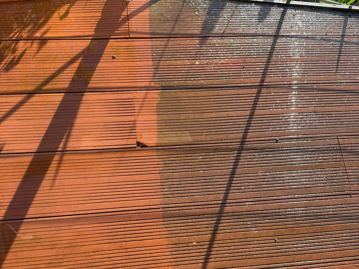 A wooden deck showing a contrast between cleaned and uncleaned areas, with one side bright and new while the other is dull and weathered