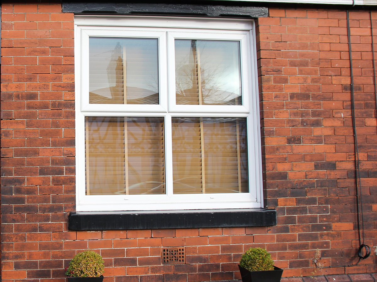 Exterior of red brick terraced house with a black front door