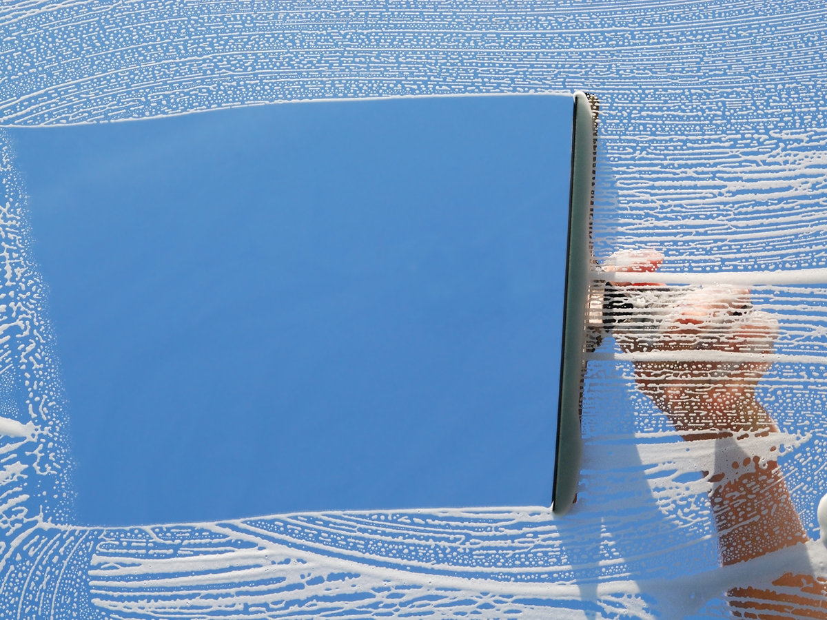 Domestic window cleaner washing a window with a squeegee